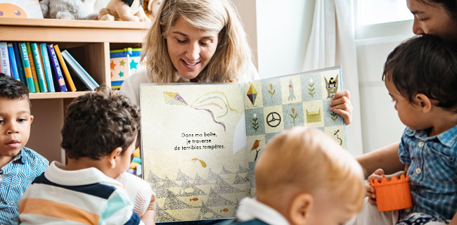 Librarian reading aloud French picture book to group of children